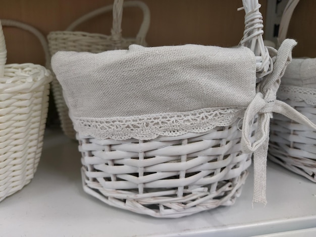 Cestini decorativi di vimini su uno scaffale in un negozio Graziosi cestini dipinti di bianco Borsa in tessuto Regalo elegante per Pasqua Elemento decorativo dell'interno di un appartamento una casa di campagna o un giardino primaverile