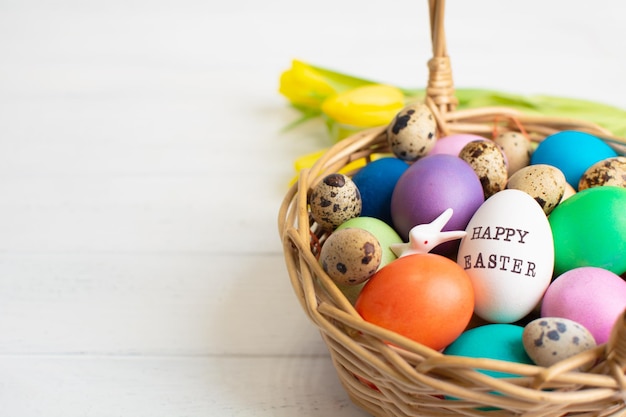 Cestini di vimini con uova colorate luminose e con testo buona pasqua e fiore