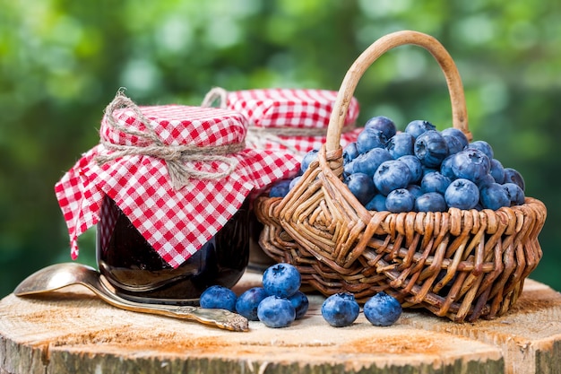 Cestino con mirtilli maturi e due vasetti di marmellata