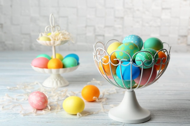 Cestino con uova di Pasqua colorate su tavola di legno bianca