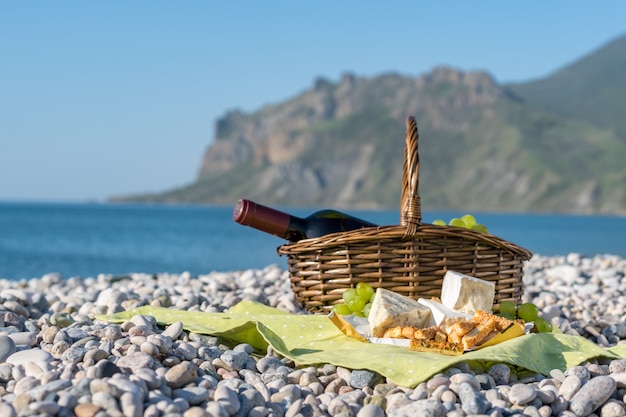 Cestino da picnic con vino, formaggio e uva