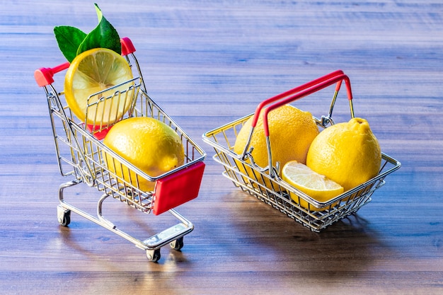 Cestino del supermercato e carrello del supermercato che trasportano foglia verde e limone.