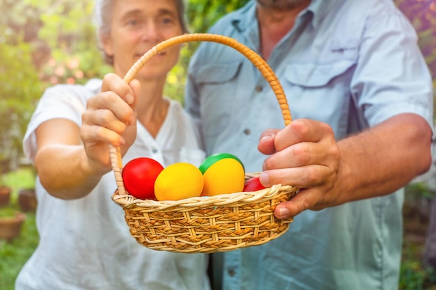 Cestino della holding delle coppie senior con le uova di Pasqua nel cortile all'aperto