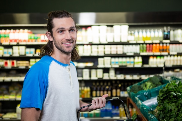 Cestino della spesa della tenuta dell'uomo in supermercato