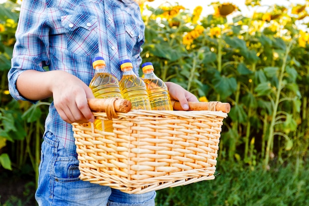 Cestino di vimini con tre bottiglie di olio di girasole nelle mani femminili.