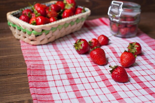 Cestino e ciotola di vetro con fragole fresche e deliziose sulla tovaglia