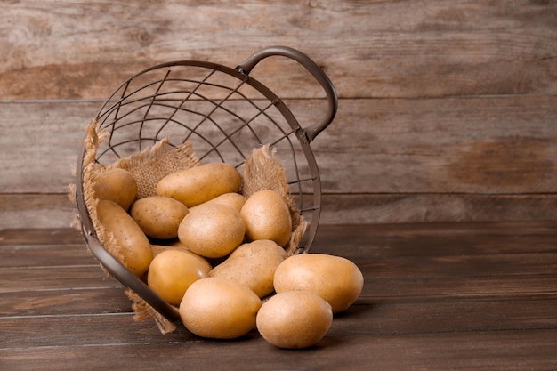 Cestino rovesciato con patate crude fresche sulla tavola di legno