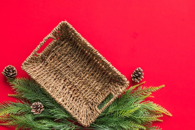 Cestino vuoto con rami di albero di Natale su sfondo rosso.