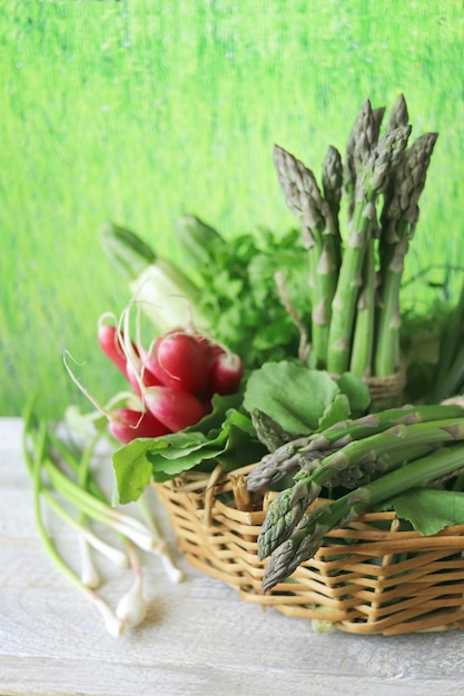 Cesto con asparagi verdi freschi, radice e prezzemolo su un tavolo di legno