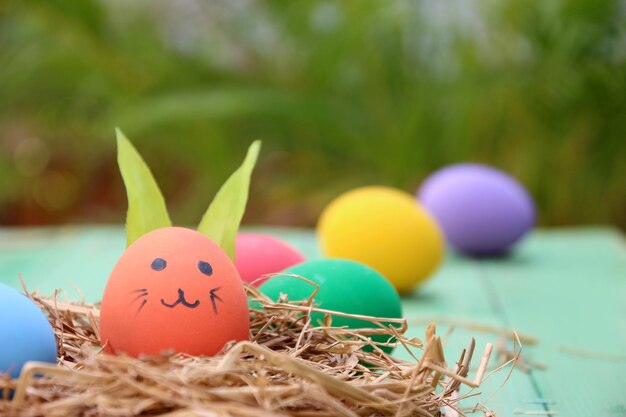 cesto di paglia con uova di Pasqua su sfondo di legno