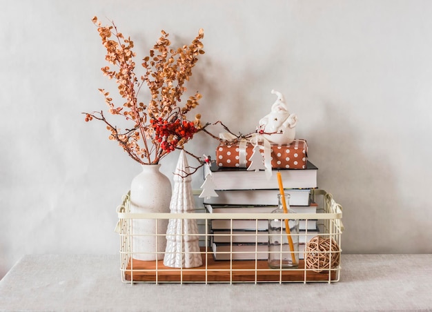 Cesto in metallo vintage con libri fiori secchi in ceramica decorazioni natalizie confezione regalo sul tavolo in un interno accogliente
