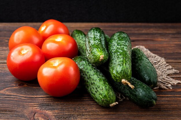 Cetrioli e pomodori freschi su fondo di legno scuro.