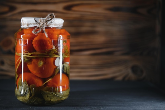 Cetrioli e pomodori in scatola con coperchi artigianali su sfondo di legno Cetrioli e pomodori con posto per il testo Scorte di cibo in scatola Scorte di raccolto per l'inverno