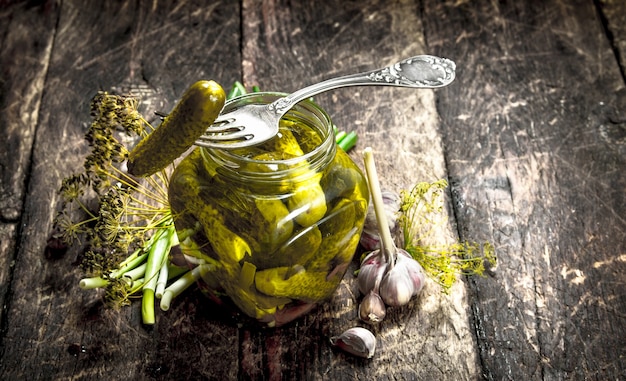 Cetrioli sottaceto con erbe e spezie sulla tavola di legno.