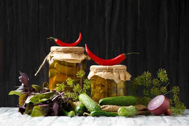 Cetrioli sottaceto in vasetti di vetro e spezie e verdure per la preparazione di sottaceti su fondo di legno vecchio