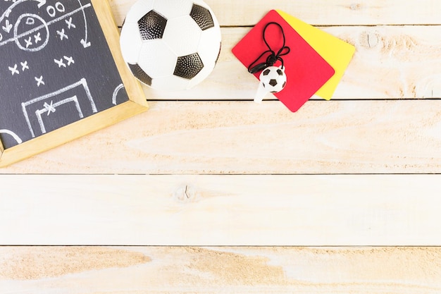 Chalk tabellone del piano di gioco e pallone da calcio su un tavolo di legno.