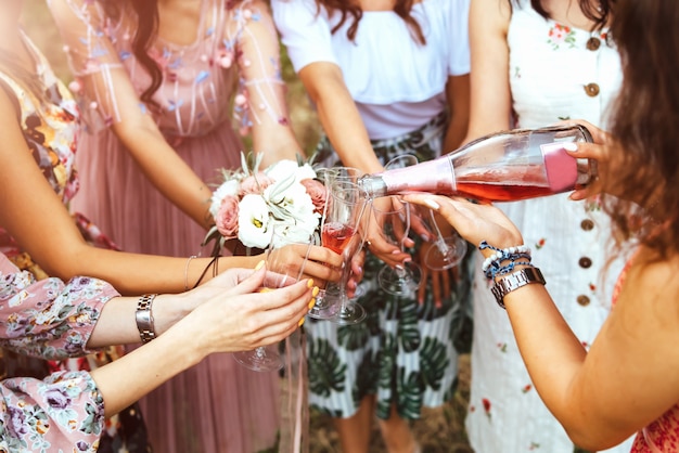 Champagne con gli occhiali nelle mani delle ragazze a addio al nubilato all&#39;aperto.