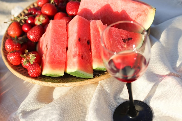 Champagne con un vassoio di frutta fragole e ciliegie su un picnic