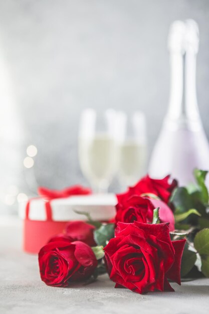 Champagne e rose rosse con bokeh. Ambientazione di San Valentino con rose rosse e regalo