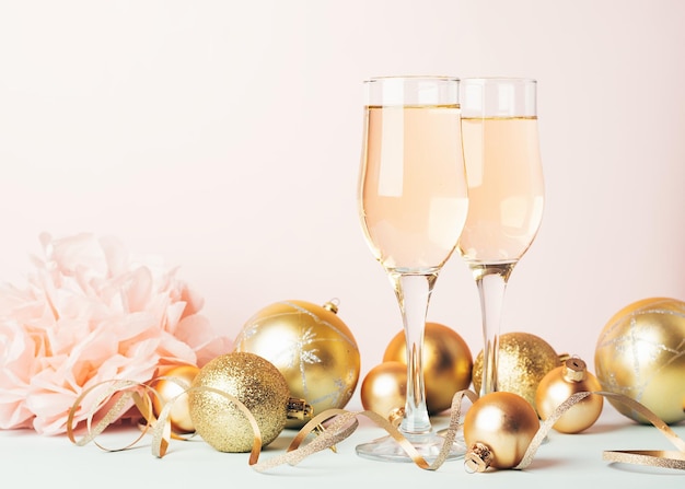 Champagne in calici di vetro palloncini d'oro stelle serpentino su uno sfondo rosa pastello delicato Concetto festivo di Capodanno