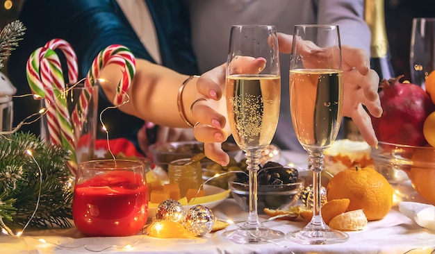 Champagne in mano sullo sfondo dell'albero di Natale. Persone.