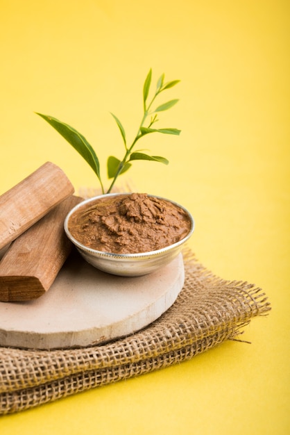 Chandan ayurvedico o pasta di legno di sandalo in una ciotola d'argento con foglie di bastoncini e foglie poste sopra sahanor sahana o base circolare in pietra per creare pasta