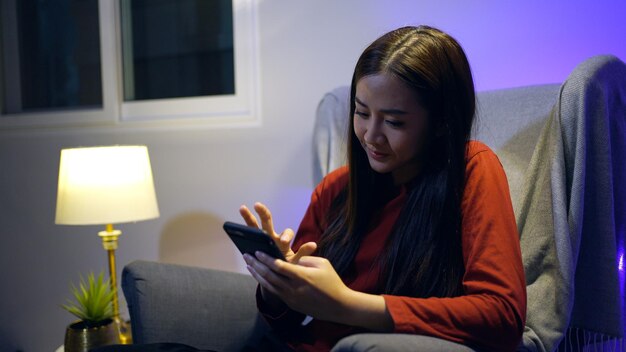 Chatta donna asiatica sul cellulare a casa. Relax e stile di vita di notte.