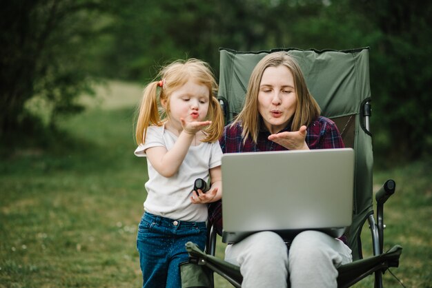 Chatta online con la famiglia sul laptop durante un picnic nella natura