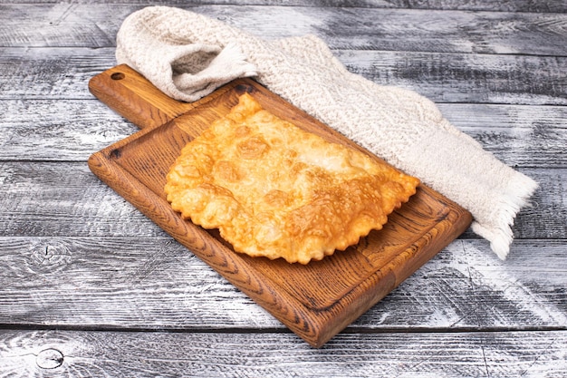 Cheburek su un piatto di legno bianco del fondo di legno