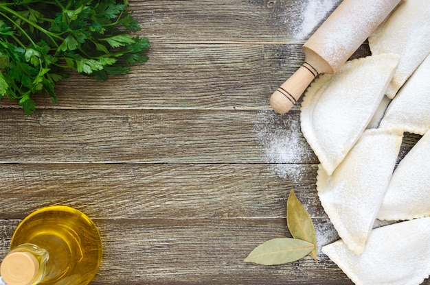 Chebureks non fritti in farina su una tavola di legno. Piatto tradizionale turco-mongolo. Semilavorati surgelati. Spazio libero per un'iscrizione.