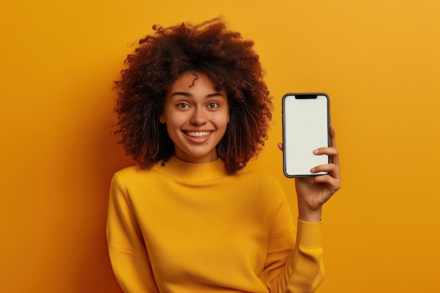 Cheerful donna afroamericana che mostra smartphone con schermo vuoto isolato su sfondo giallo