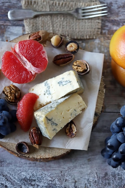 Cheeseboard Formaggio con noci pompelmo e uva su una tavola di legno Spuntini sani