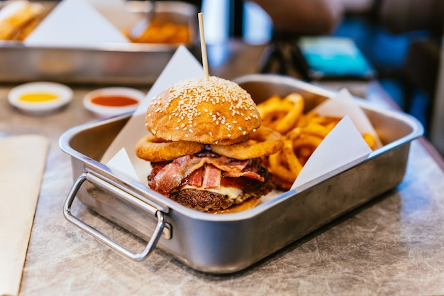 Cheeseburger con manzo alla griglia medio-raro, bacon croccante, anelli di cipolla.