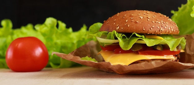 Cheeseburger e pomodoro su sfondo scuro Fast food closeup