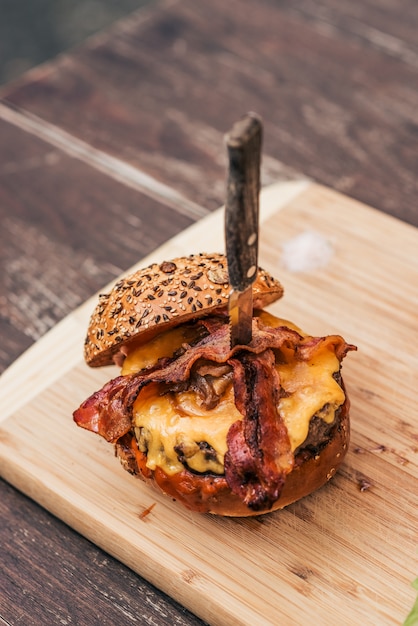 Cheeseburger saporito del bacon sulla scheda di legno.