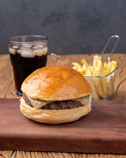 Cheeseburger su tavola di legno con patatine fritte e soda