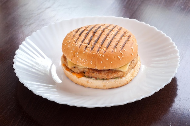 Cheeseburger succoso con formaggio su un piatto bianco