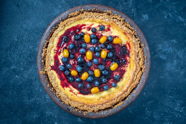 Cheesecake ai mirtilli e all'olivello spinoso su sfondo scuro, vista dall'alto, primo piano