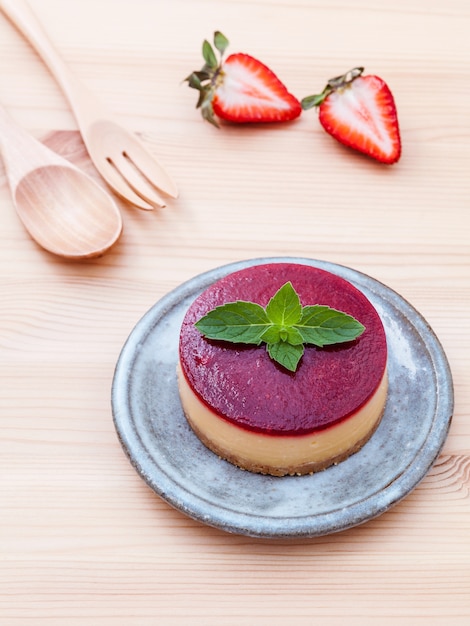 Cheesecake alla fragola con foglie di menta fresca su fondo di legno.