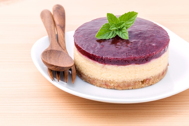 Cheesecake alla fragola con foglie di menta fresca su fondo di legno.