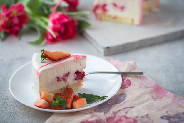 Cheesecake classica New York a fette Pezzo di cheesecake con fragole fresche e tulipani