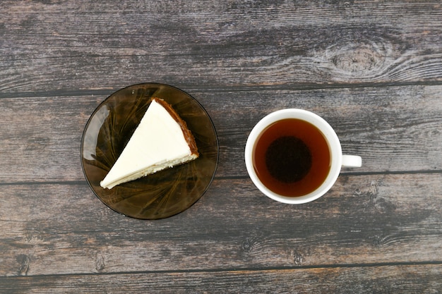 Cheesecake con caffè su un legno scuro. . Una cheesecake accanto ad essa su un legno marrone. tazza retrò. Caffè in una caffetteria, copia.