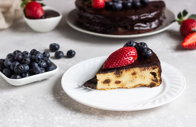 Cheesecake con uvetta decorata con glassa al cioccolato e fragole e mirtilli.