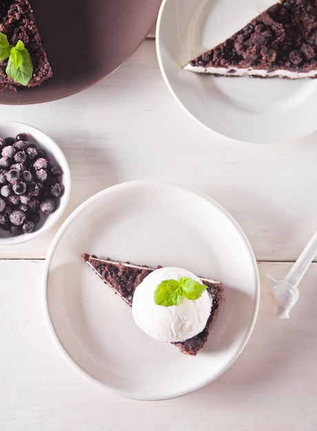 Cheesecake cremoso con cioccolato, ribes nero, gelato e foglie di menta per la decorazione
