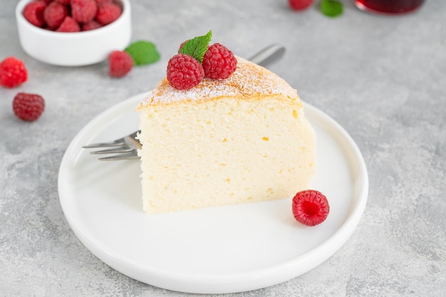 Cheesecake di cotone giapponese su un supporto su uno sfondo di cemento grigio con lamponi freschi