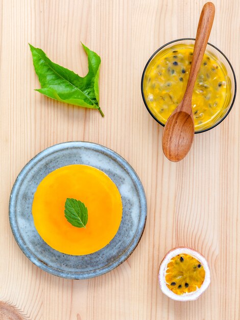 Cheesecake di frutto della passione con foglie di menta fresca su fondo di legno.