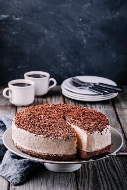 Cheesecake fredda al cioccolato su un piatto su fondo rustico in legno