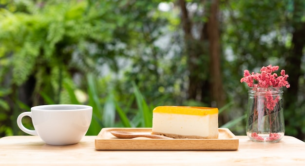 Cheesecake frutto della passione e tazza di caffè caldo sul vassoio in legno e tavolo