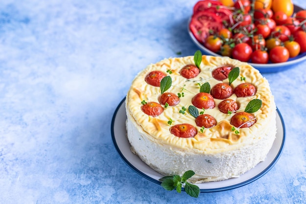 Cheesecake salata con pomodori decorata con fondo cemento blu menta