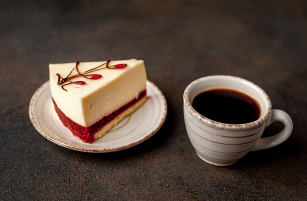 Cheesecake - torta su un piatto bianco e caffè su sfondo di pietra con copia spazio per il testo